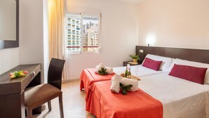 A hotel room with a desk, two beds, a chair, a window with curtains, and a view of buildings. - Benidorm Levante Beach 12B, Benidorm, Spain (Benidorm)