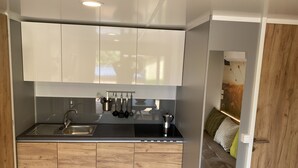 A compact kitchen with wooden cabinets, a stainless steel sink, and hanging utensils. - Mountain View Lodge XL (1) - Idro (Idro)