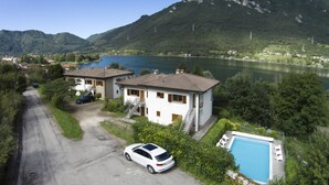 A residential area with two houses, a swimming pool, and a lake with mountains in the background.