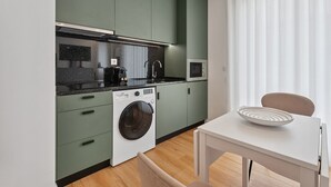 Una cocina pequeña equipada con lavadora, microondas y lavaplatos.
