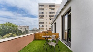 Un balcon avec du gazon synthétique, une table et des chaises.