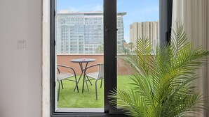 Un balcon avec une table et des chaises, un pot de fleurs et une vue sur les bâtiments en arrière-plan.