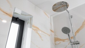 A modern bathroom with a marble wall and a shower with a handheld showerhead. - GuestReady - Tutti Frutti Studio - Cherry (Porto)