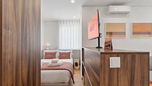 Ein Hotelzimmer mit einem Bett, einem Holztisch, einem Fernseher und einer Wandklimaanlage.