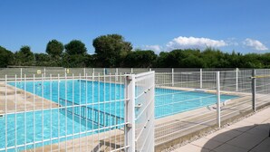 Una piscina con una cerca blanca y un cielo azul despejado.