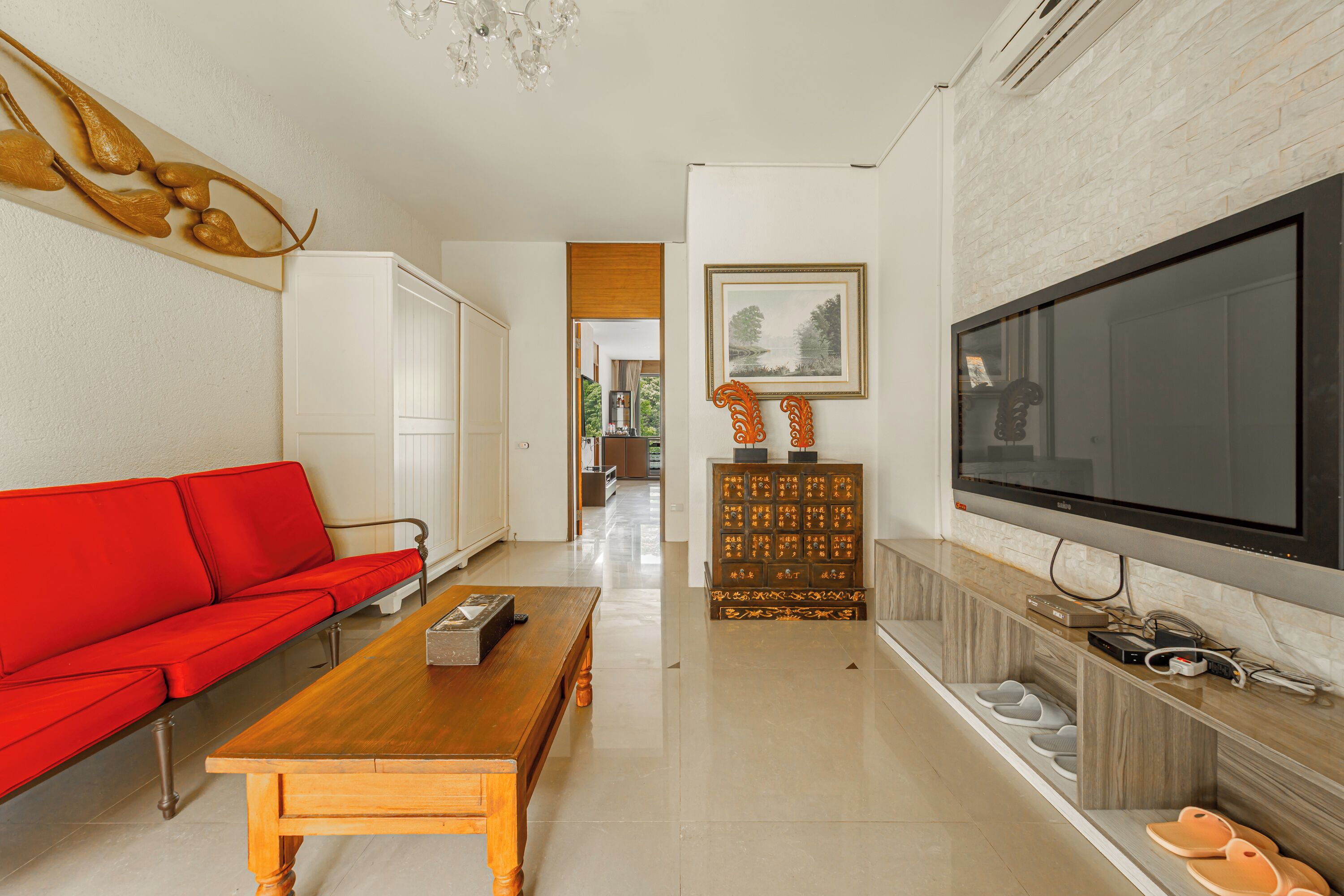 A modern living room with a red sofa, wooden coffee table, and a large flat-screen TV.