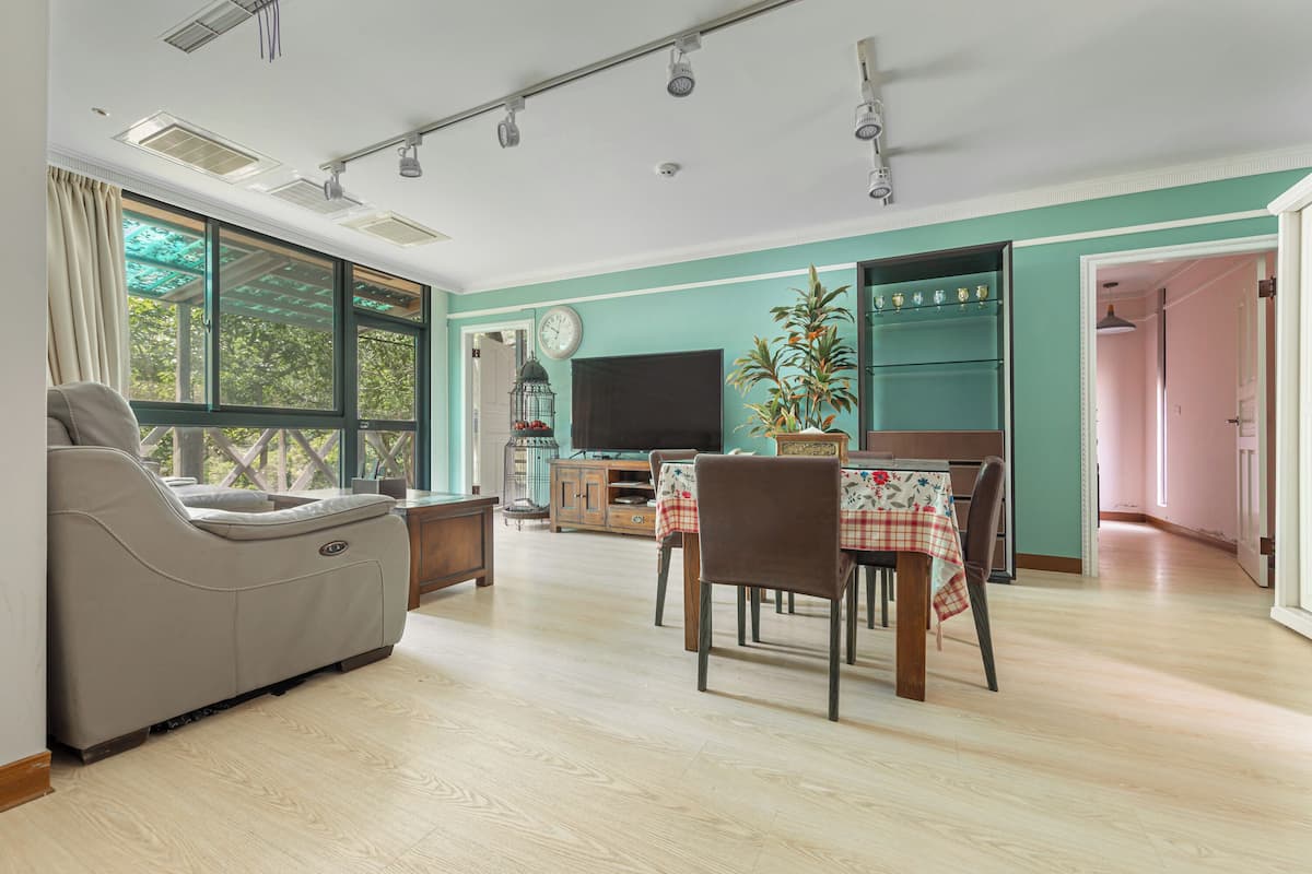 Una sala de estar con sofá, televisión, mesa de comedor, sillas y una zona de cocina con horno.