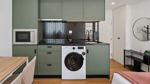 A compact kitchen with a built-in microwave, a washing machine, and a sink. - GuestReady - Tutti Frutti Studio - Avocado (Porto)