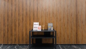 A black metal shelf with two informational signs against a wooden slatted wall. - GuestReady - Tutti Frutti Studio - Avocado (Porto)