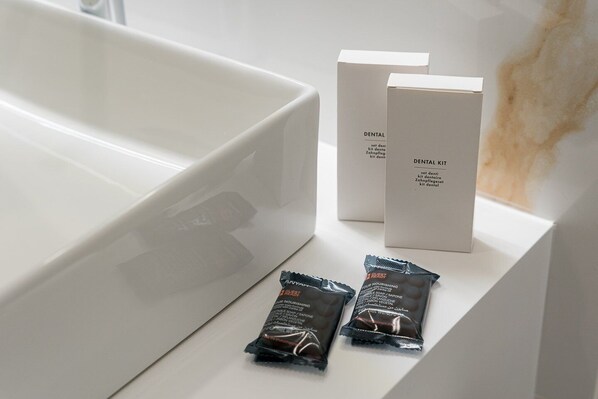 A bathroom with a white bathtub, two white boxes labeled "DENTAL KIT," and two small packets of "YOUR NOURISHING" soap.