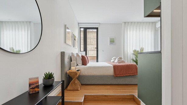 A modern bedroom with a bed, bedside table, and a view of the city. - GuestReady - Tutti Frutti Studio - Avocado (Porto)