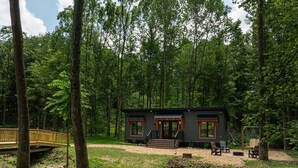 Eine Hütte mit Terrasse, einer kleinen Sitzgelegenheit im Freien und einem Bach in der Nähe.