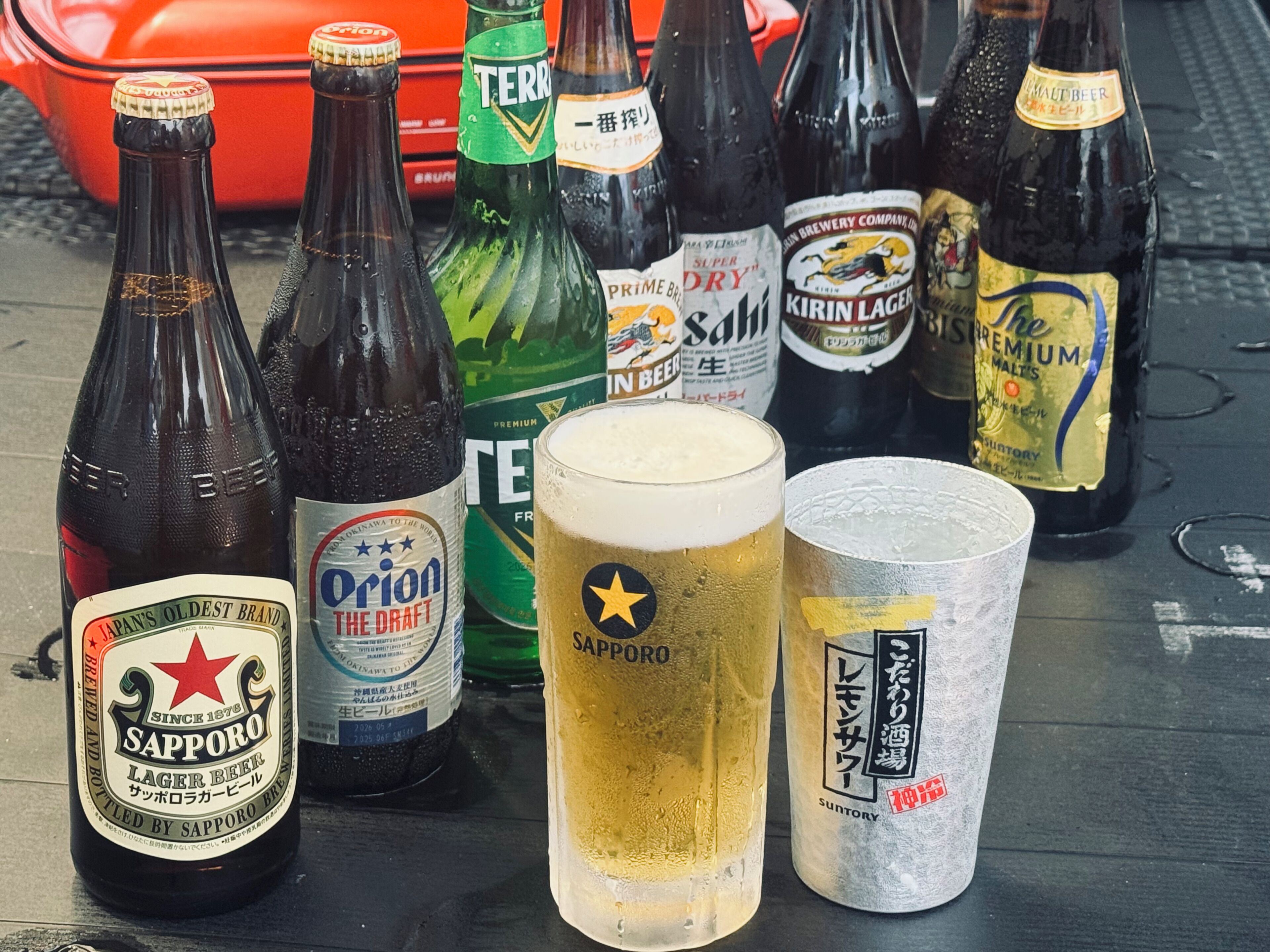 A variety of beer bottles and glasses on a table.