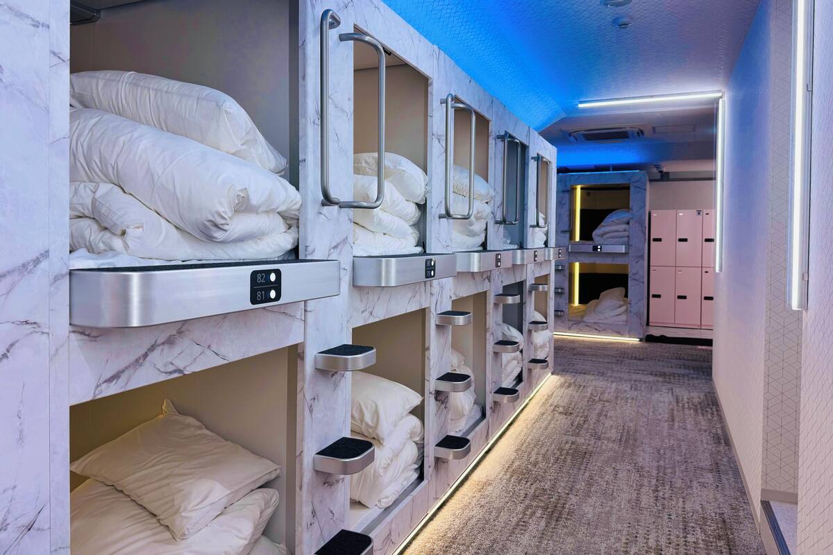 Une chambre d’hôtel équipée de lits superposés, chacun doté d’un panneau de commande et de compartiments de rangement.