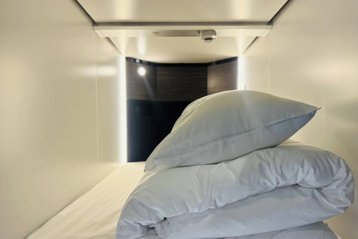 Un lit bien fait, agrémenté de plusieurs oreillers, dans une chambre d’hôtel moderne.