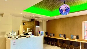 Ein Hotel-Empfangsbereich mit Marmorboden, einer Rezeption, einer Globen-Dekoration und einer Holzwand.