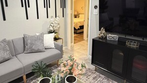 Una sala de estar moderna con un sofá gris, un mueble de entretenimiento negro y un televisor de pantalla plana.