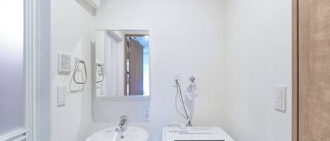 A bathroom with a white sink, a mirror, and a white portable heater.