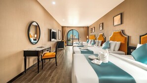 Habitación de hotel con una cama grande, un escritorio, una silla, un televisor y vistas al exterior.