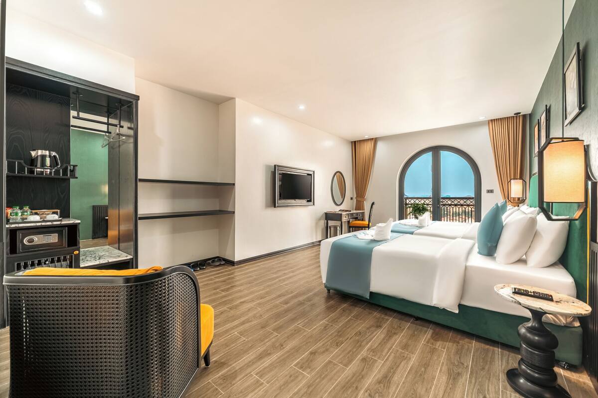 A modern hotel room with a bed, a TV, a dining area, and a balcony.