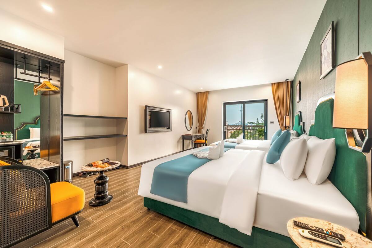 A hotel room with a bed, a desk with a chair, a TV, and a window with curtains.