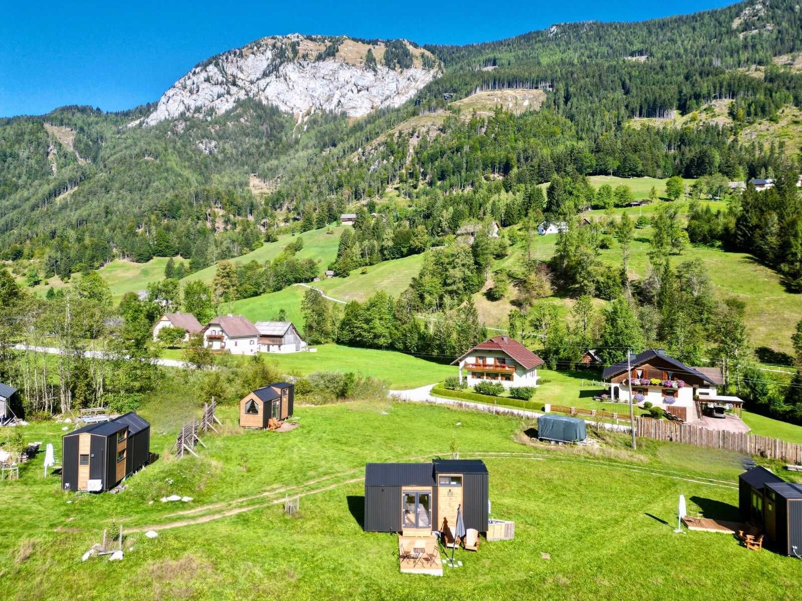 Paesaggio rurale con case, una montagna e cielo sereno.