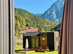 A small cabin with a red roof, a wooden deck, and a white umbrella. - The Alpine Experience 1 by Tiny Away (Zell-Freibach)