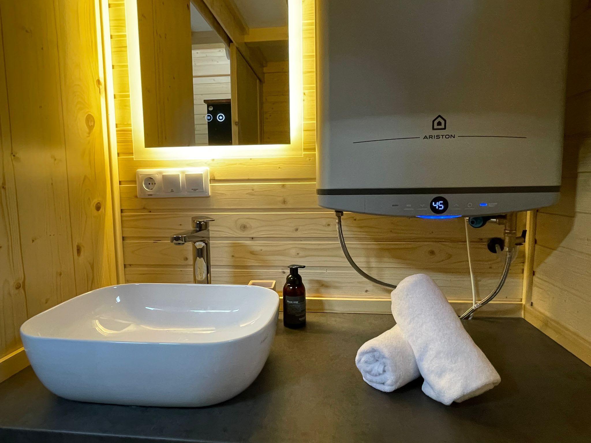 A bathroom with a white sink, a towel, and a water heater.