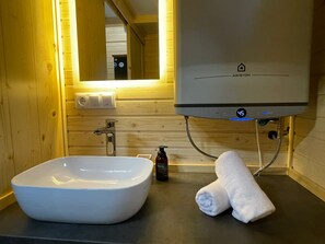 Un baño con lavamanos blanco, una toalla y un calentador de agua.