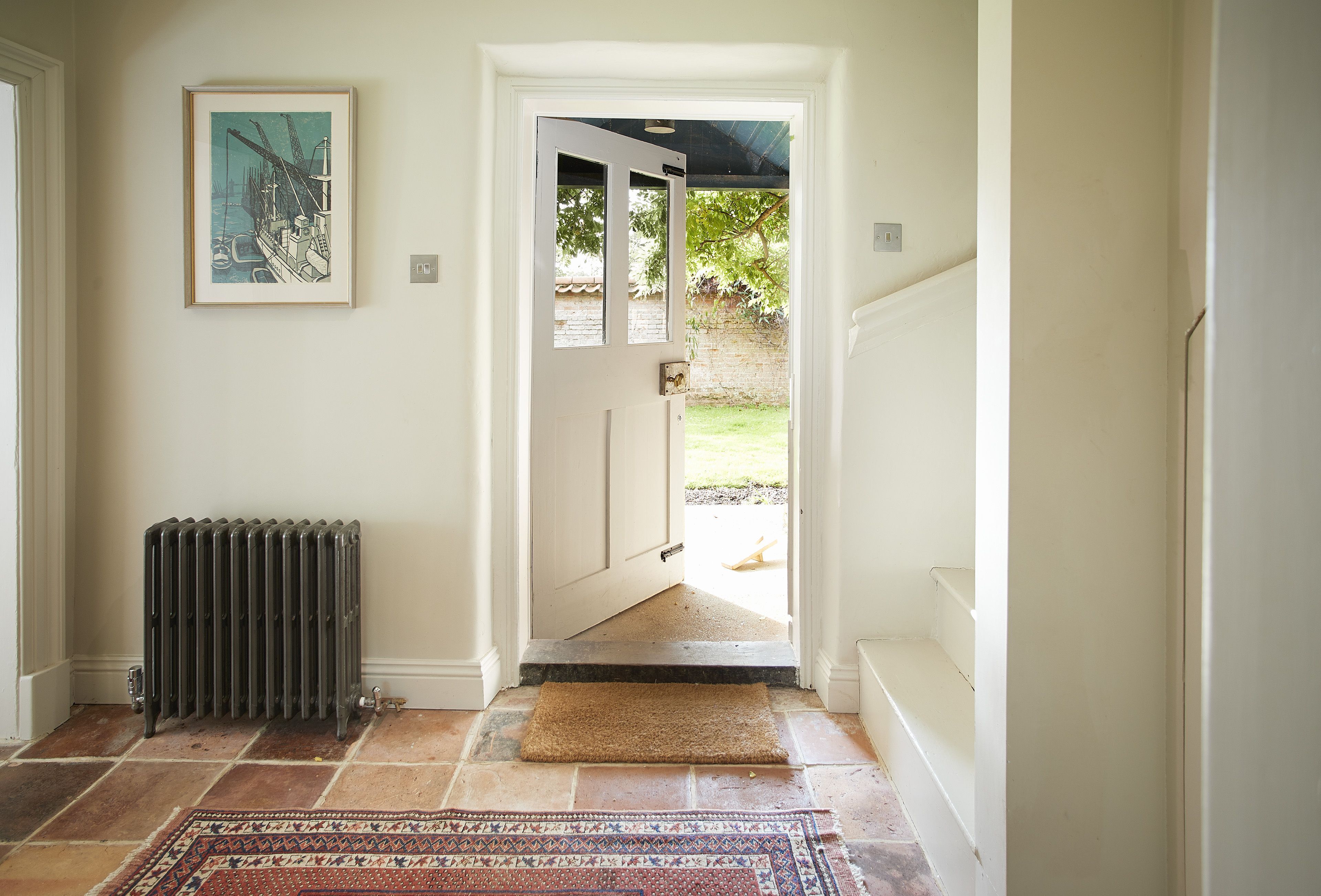 A hallway with a radiator, a framed picture on the wall, and a rug on the floor.