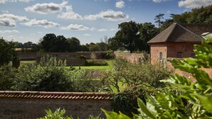 A brick building with a tiled roof, surrounded by a well-maintained garden and a brick wall.