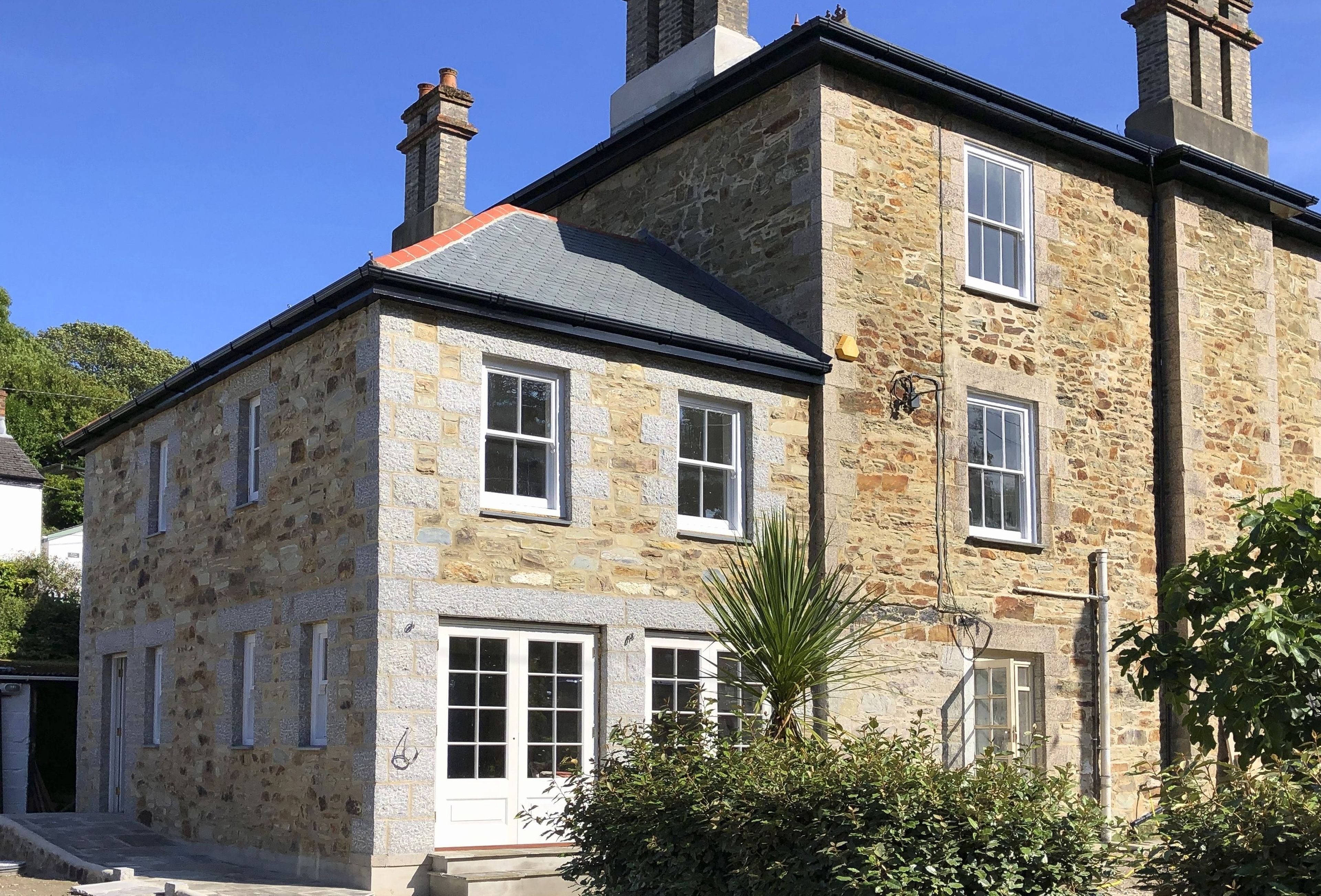 A stone building with multiple windows and a chimney.