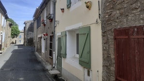 A narrow street with buildings on either side, featuring stone walls, wooden shutters, and potted plants. - CORBIERES HOUSE NEAR LAGRASSE (Saint-Pierre-des-Champs)