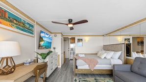A hotel room with a bed, a sofa, a desk, and a ceiling fan.