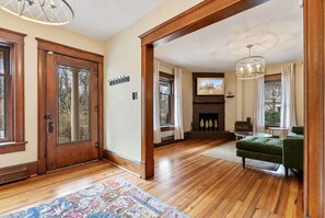 A spacious living room with hardwood flooring, a fireplace, and a green sofa.