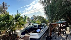 Un bote amarrado en una playa arenosa, con una mesa y sillas cerca.