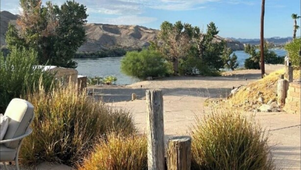 Un área al aire libre con vistas panorámicas a un lago, rodeado de colinas y vegetación.