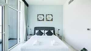 Una camera d'albergo moderna con un letto grande, due quadri con fiori appesi al muro, una lampada a soffitto e una porta scorrevole in vetro che dà su un balcone.