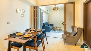 Zona pranzo moderna con tavolo in legno e sedie imbottite blu, un tavolino rotondo e un divano blu sullo sfondo.