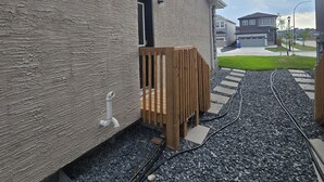 Un edificio con facciata strutturata, una recinzione in legno e un vialetto sterrato.