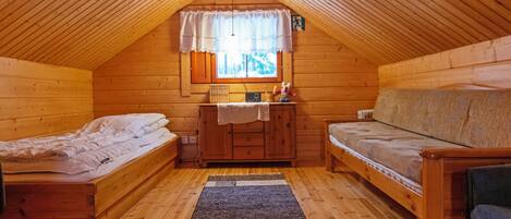Ein gemütliches Schlafzimmer unter dem Dach mit zwei hölzernen Betten, einem kleinen Tisch und einer Couch.