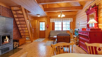 L’intérieur d’un chalet chaleureux, avec une cheminée, des meubles en bois et une commode rouge.