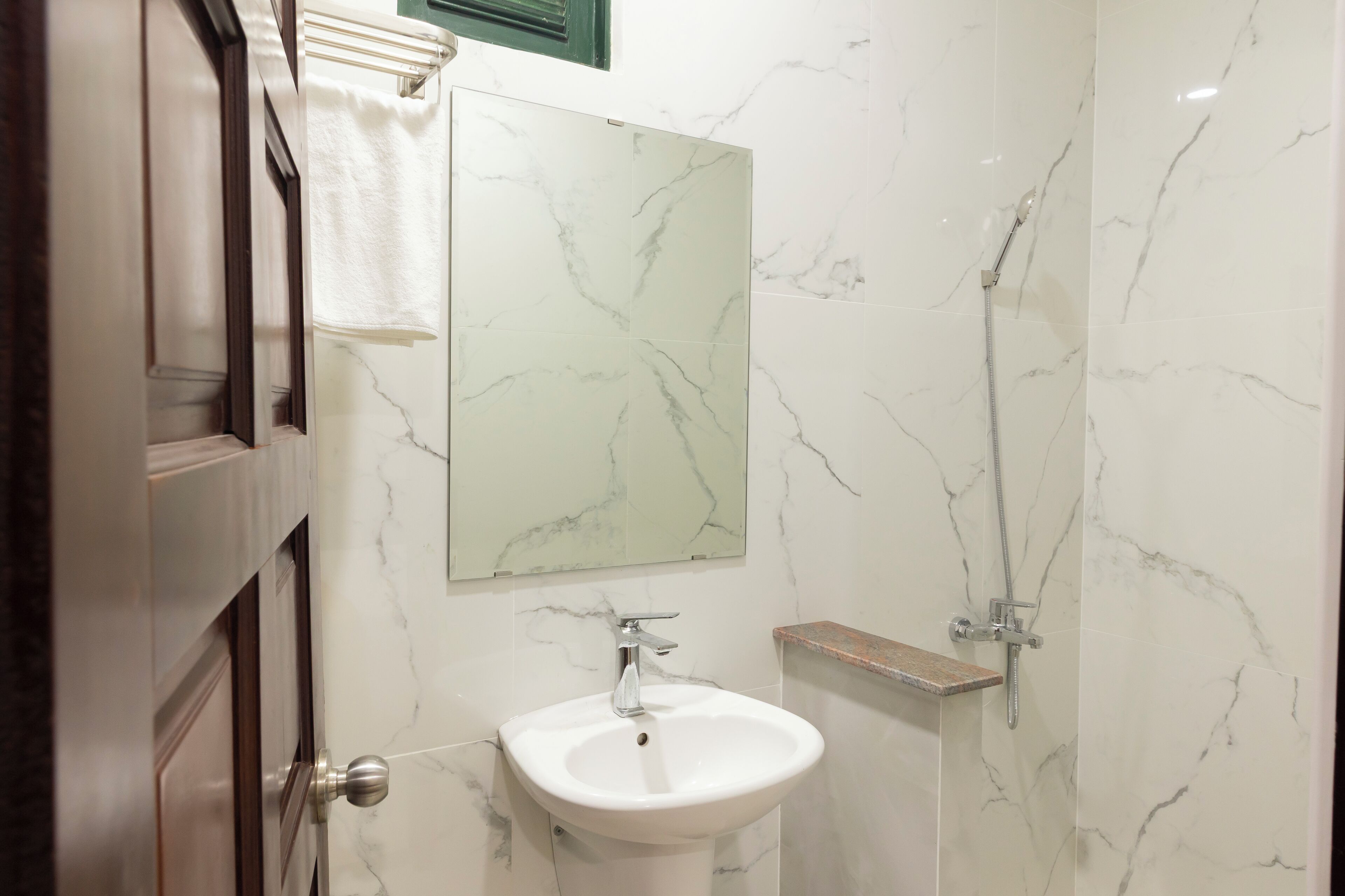 Une salle de bain avec un lavabo en marbre blanc, un miroir et une douche.