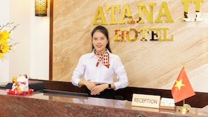 A reception desk at Atana II Hotel with a marble wall background, a flag, and a reception sign. - Atana Saigon Boutique Hotel II (Ho Chi Minh City)