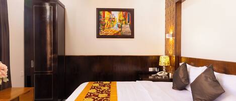 Una camera d'albergo con un letto, un comodino, una lampada, un armadio e un quadro appeso al muro.