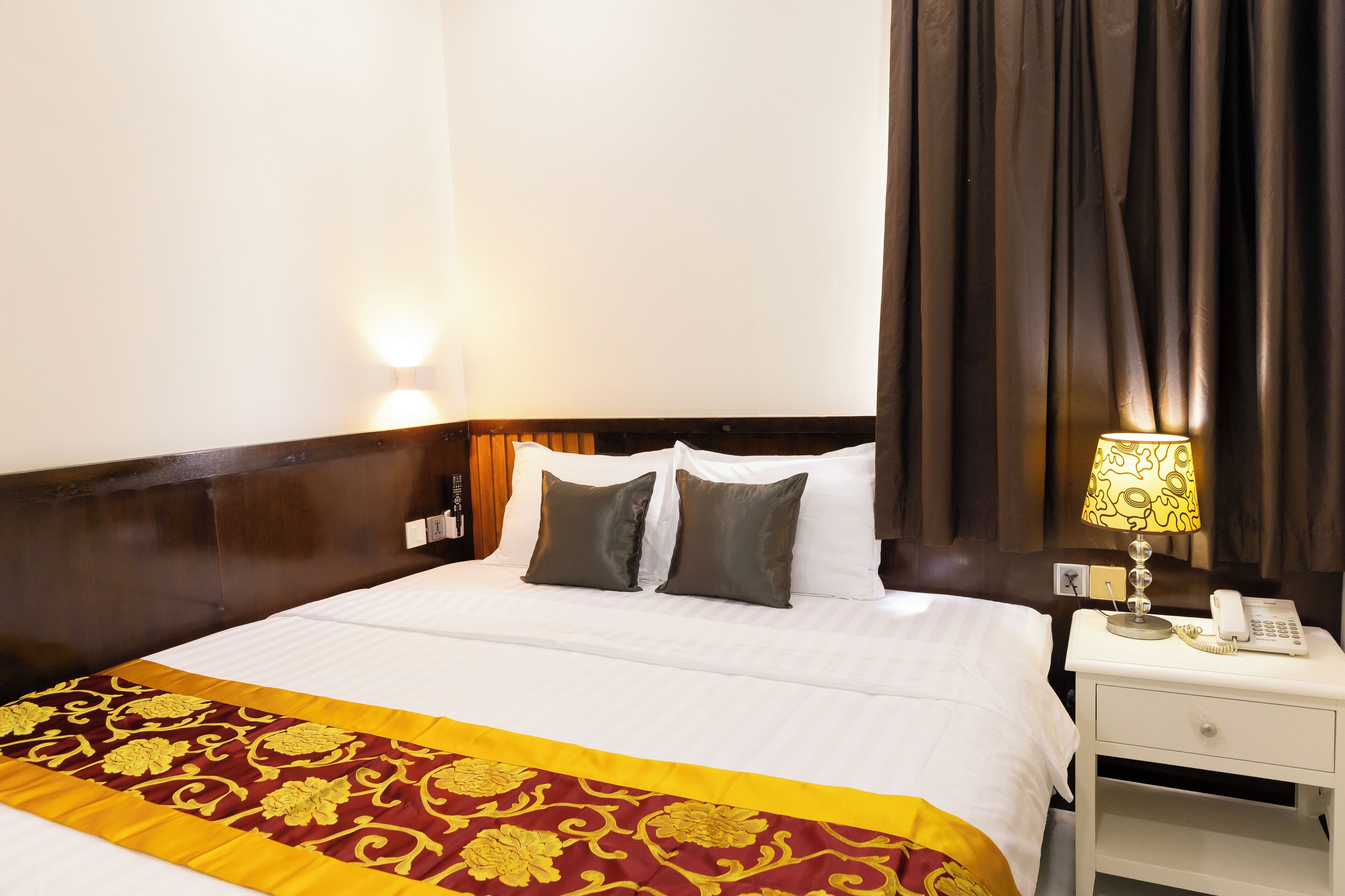 Une chambre d’hôtel avec un lit bien fait, une lampe de chevet, un téléphone et une table de chevet.