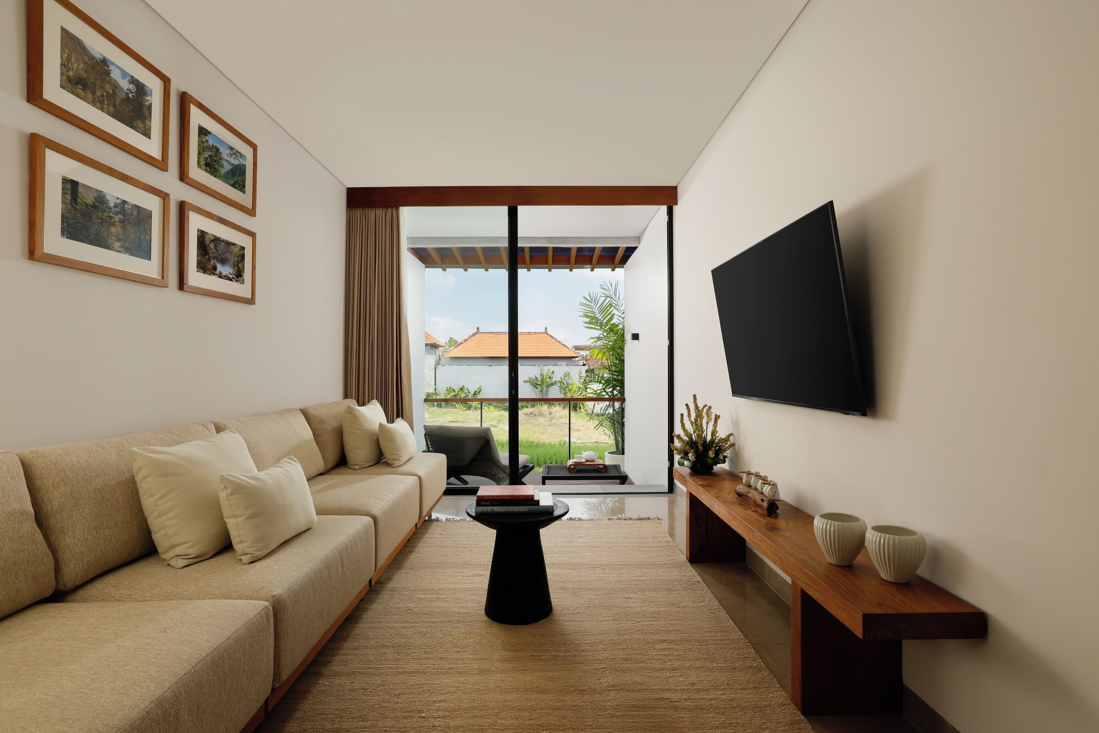 A modern living room with a sofa, a coffee table, a TV, and framed pictures on the wall.