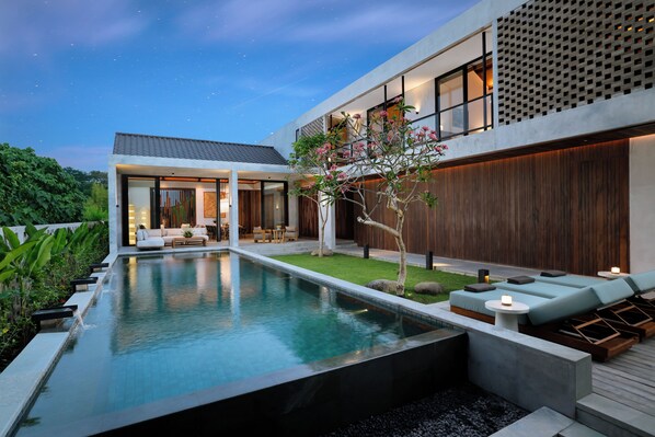 Ein modernes Haus mit Swimmingpool, Sitzgelegenheit im Freien und einem gepflegten Garten.