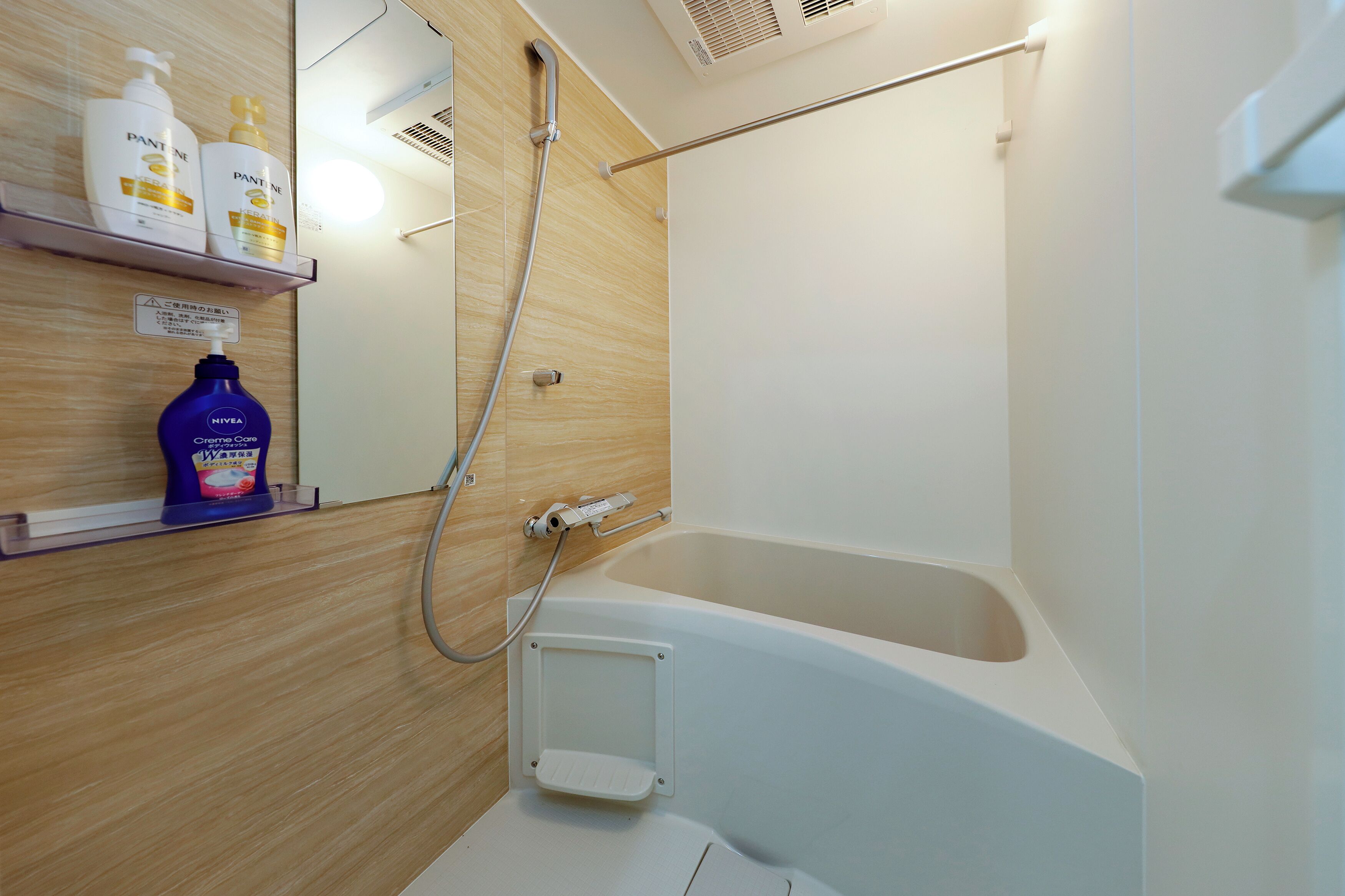 A modern bathroom with a bathtub, a shower, and a shelf with toiletries.