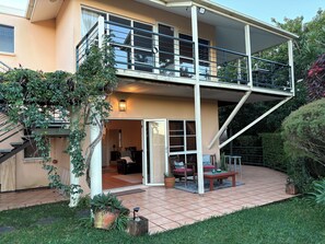 A two-story house with a balcony, a staircase, and a patio area with outdoor furniture. - RiverRock Retreat Maroochy, Sunshine Coast: 6 bed 6, bath, 15 min from beach (Maroochy river)